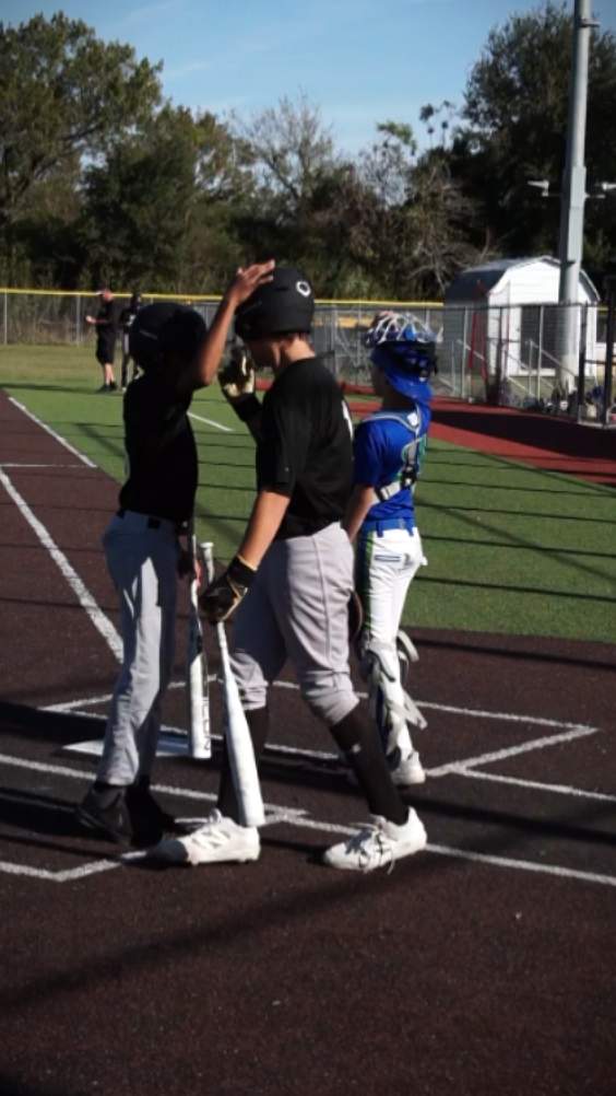 Youth baseball players on a field in a social-ready vertical composition
