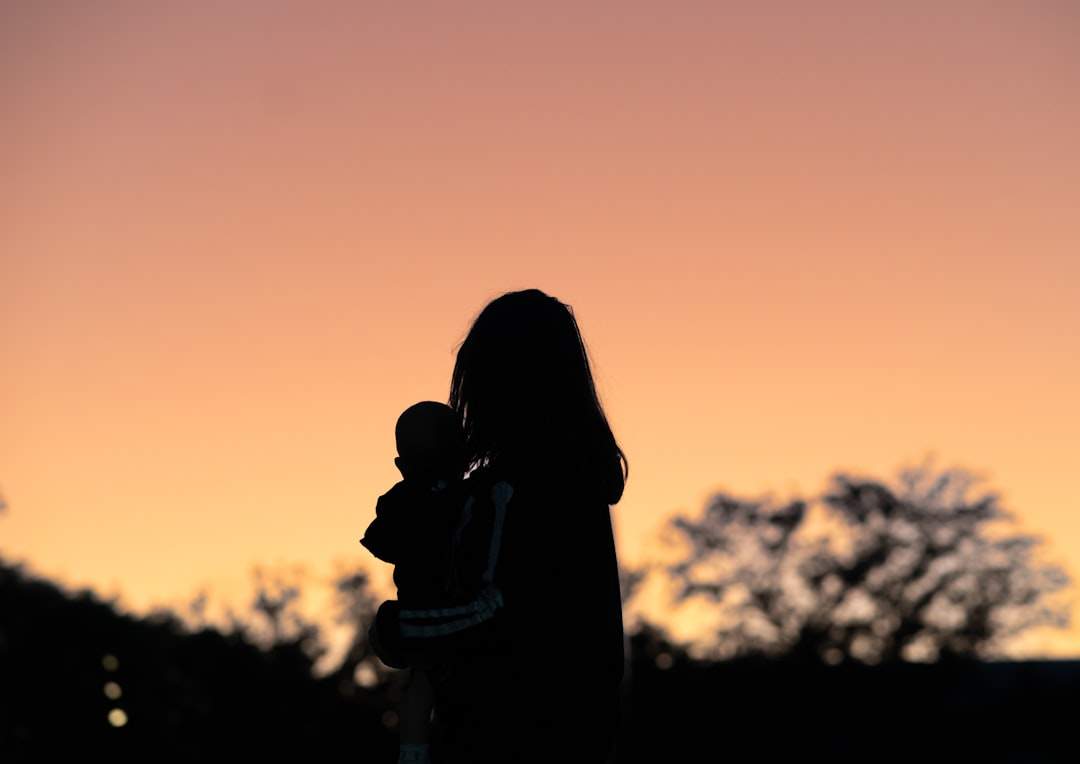A silhouette of a mother and child against a sunset.