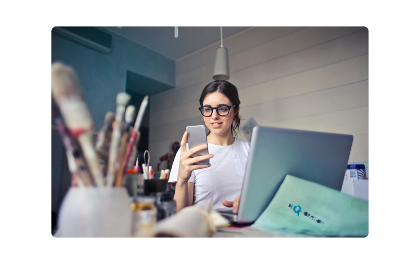 Mujer usando un teléfono inteligente y una computadora portátil, destacando el crecimiento del comercio electrónico móvil para negocios y compras en línea.