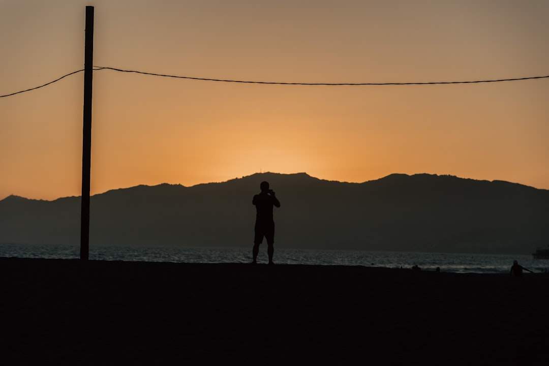 A silhouette of a person standing against a sunset with headphones on.