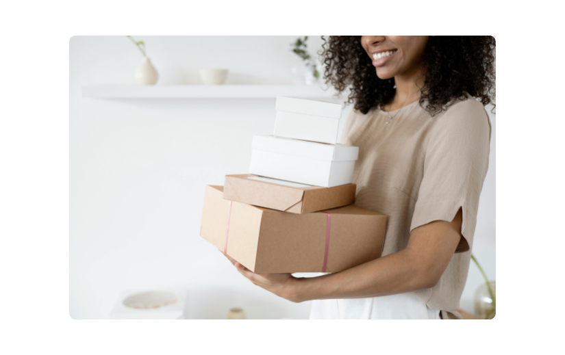 امرأة مبتسمة تحمل حزمًا مكدسة ، تعرض أفكارًا صاخبة لبدء عمل تجاري صغير عبر الإنترنت من المنزل.