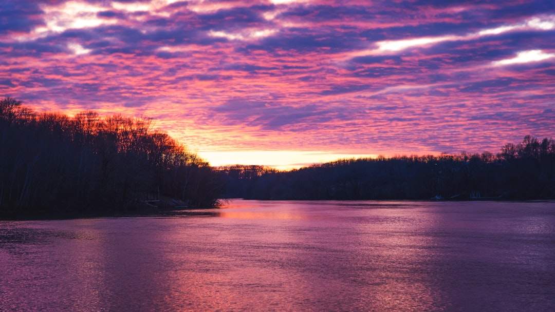 A beautiful sunrise over a calm and serene lake, with vibrant colors painting the sky.