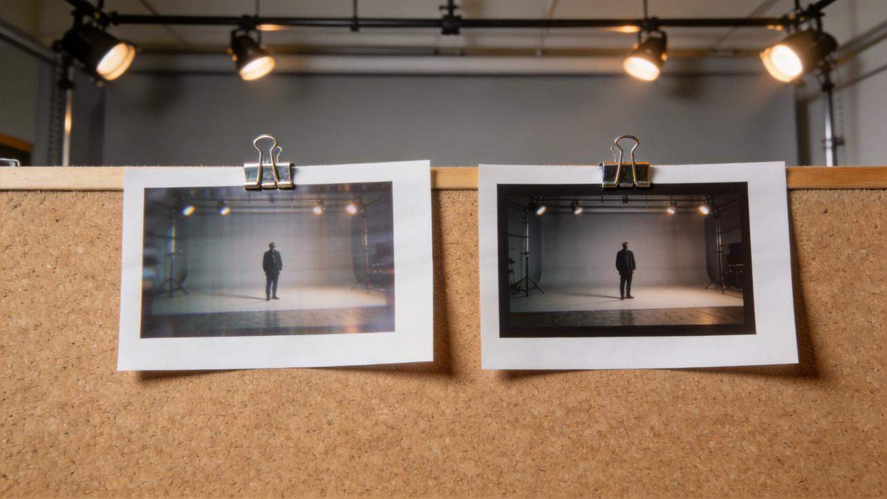Two printed studio photos clipped to a cork board under overhead lights