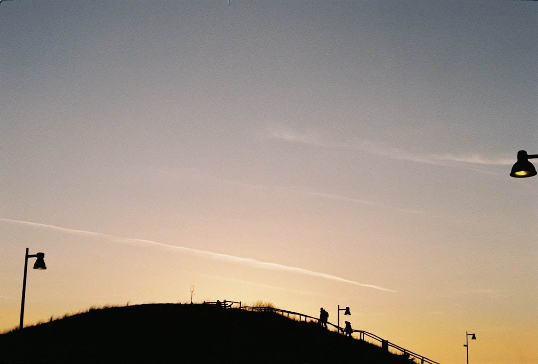 A silhouette of a graduate tossing their cap in the air at sunset.