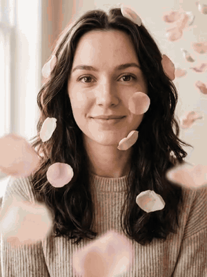 Portrait of a woman with soft pink petals floating in front of her face
