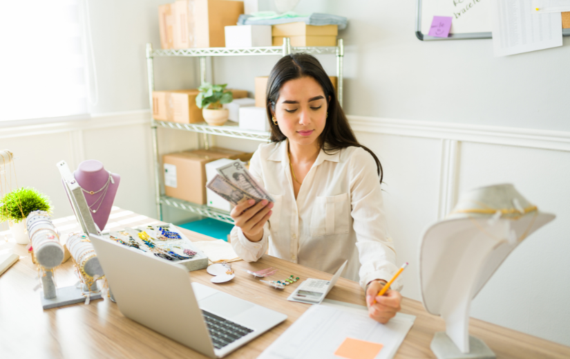 Antreprenor care administrează o afacere online de bijuterii, numărând numerar și organizând inventarul—ideal pentru o strategie profitabilă pe eBay.