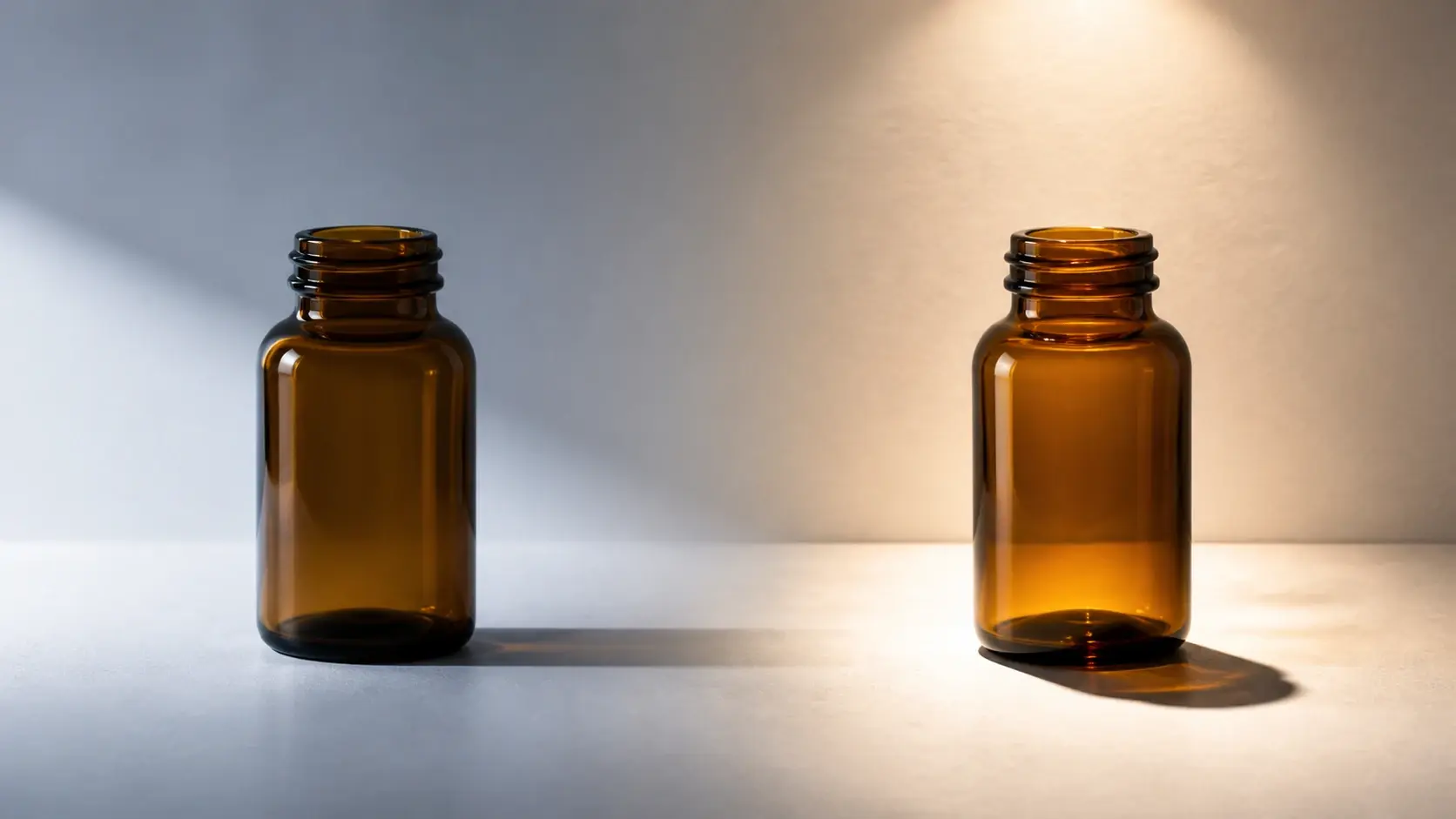 Two amber glass bottles on a gray and beige background with side lighting