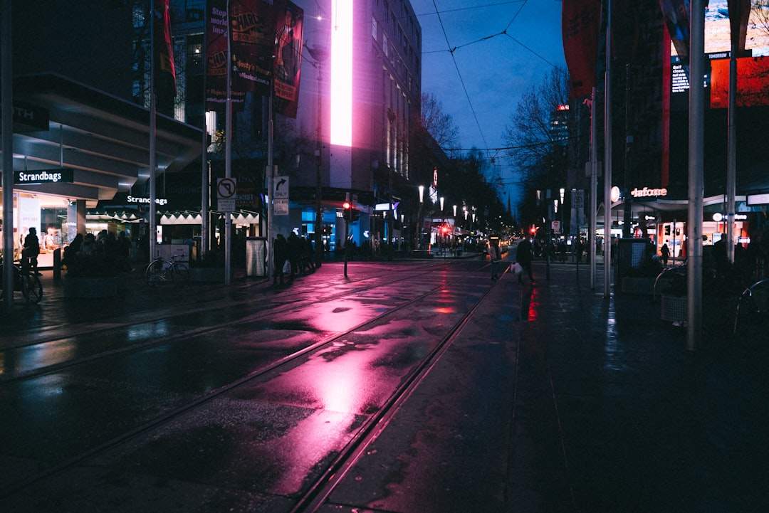 Neon-lit street at dusk with reflective puddles