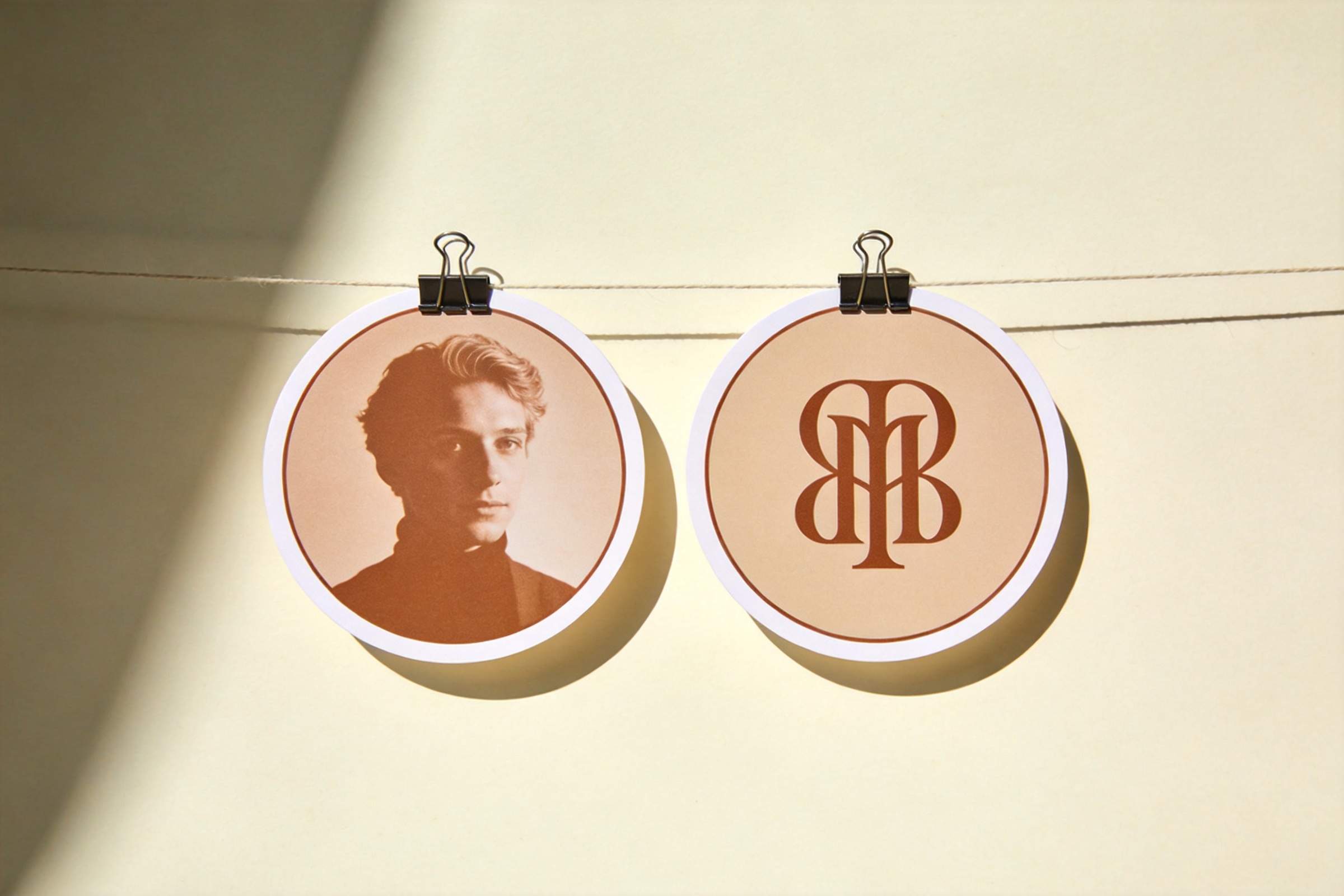 Two round profile icons hanging on a line, one with a portrait and one with a monogram logo