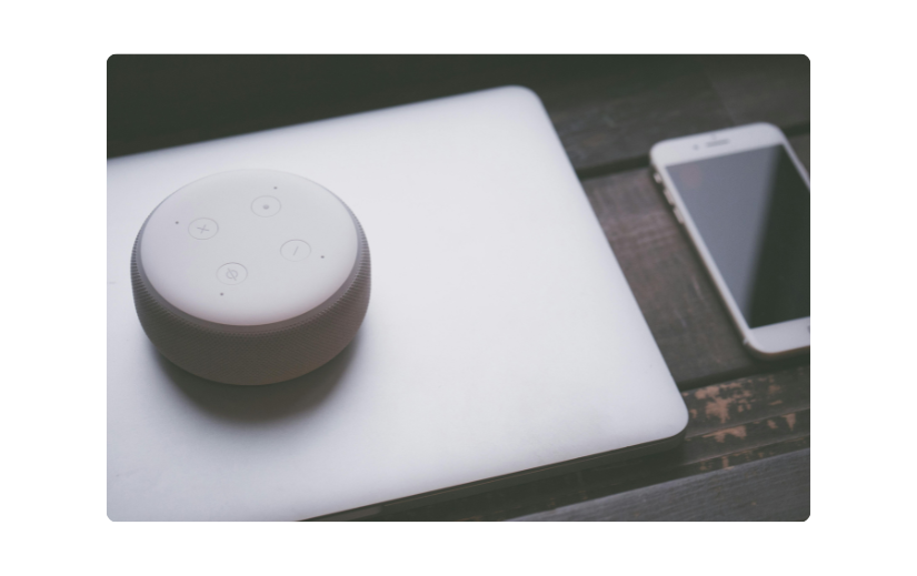 Altoparlante intelligente su un laptop accanto a uno smartphone, ideale per la promozione dei prodotti Amazon di gadget tecnologici.