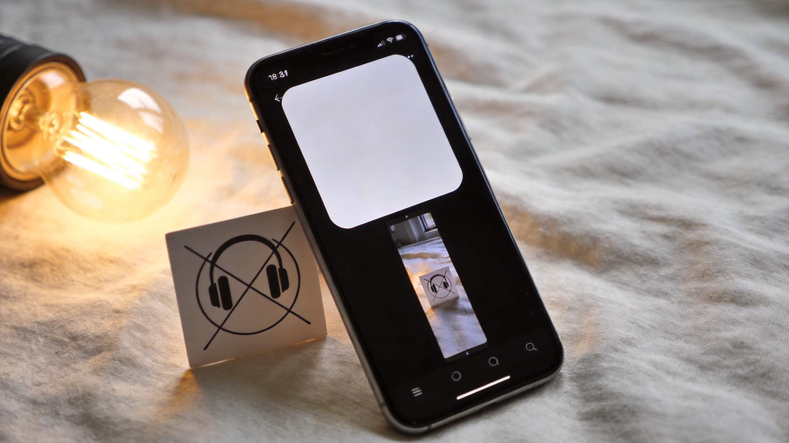 Smartphone editing app open beside a glowing bulb and a small printed icon card