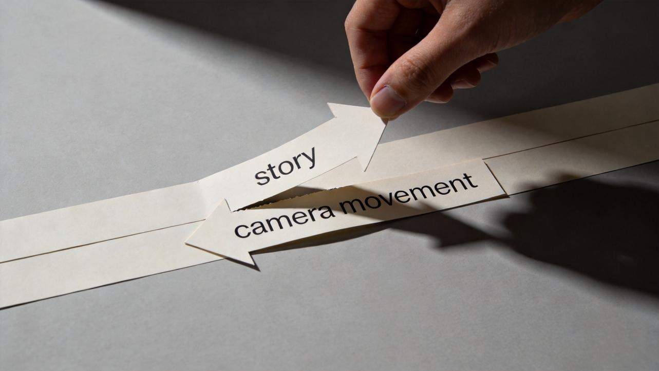 Hand moving arrow labels marked "story" and "camera movement" on paper