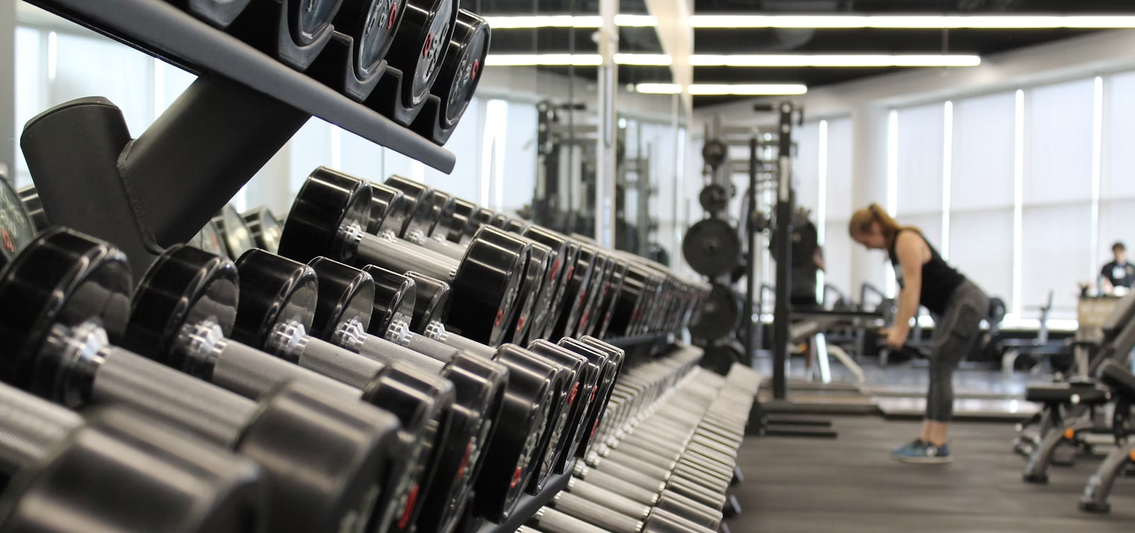 A person lifting weights in a gym with motivational text overlay.