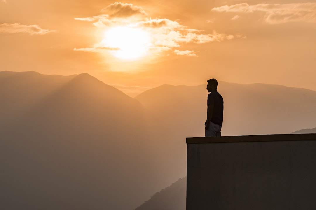 A lone student standing on a mountaintop at sunrise, looking out at a vast and beautiful landscape, symbolizing future possibilities.