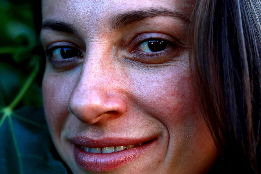 A close-up portrait of a smiling person with a subtle portrait filter applied, smoothing skin and enhancing their eyes.