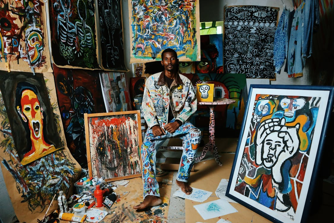 Artist surrounded by canvases and paints in studio
