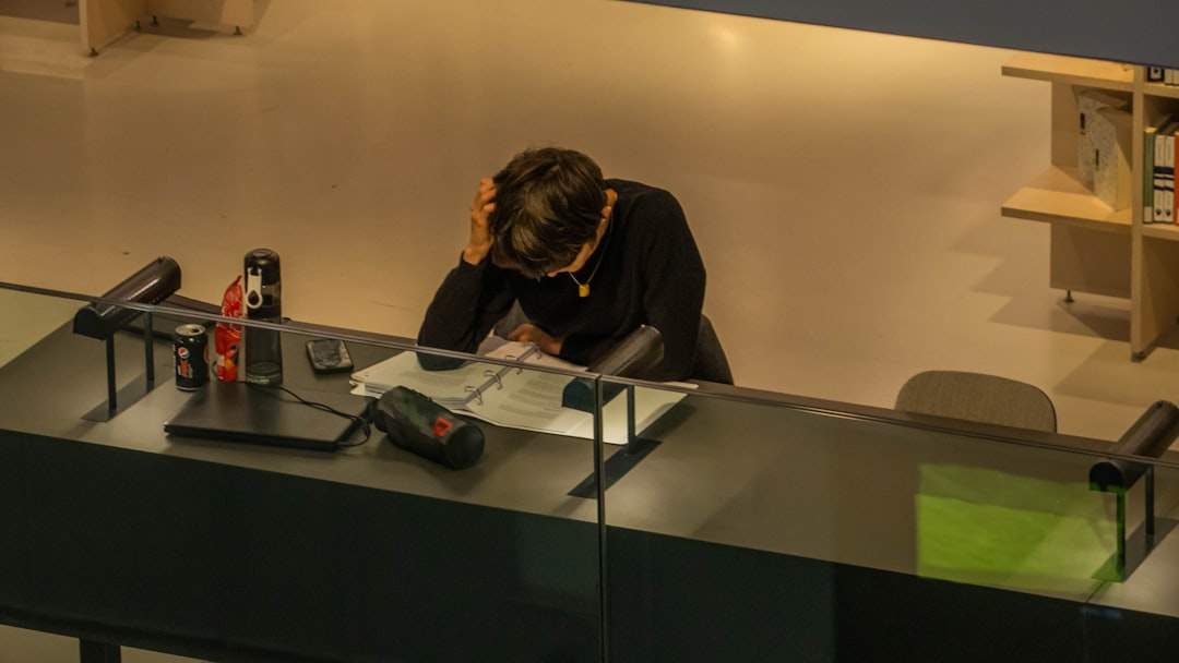 A person sitting at a desk with headphones on, editing a video on a computer that shows audio waveforms.