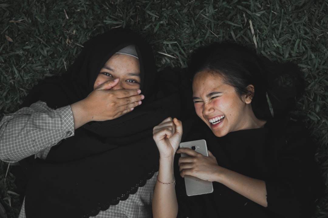 Friends laughing together while looking at a phone.