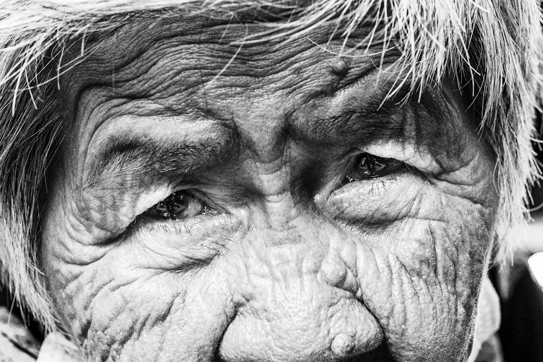 A dramatic black and white portrait of an elderly person, highlighting wrinkles and expressions.