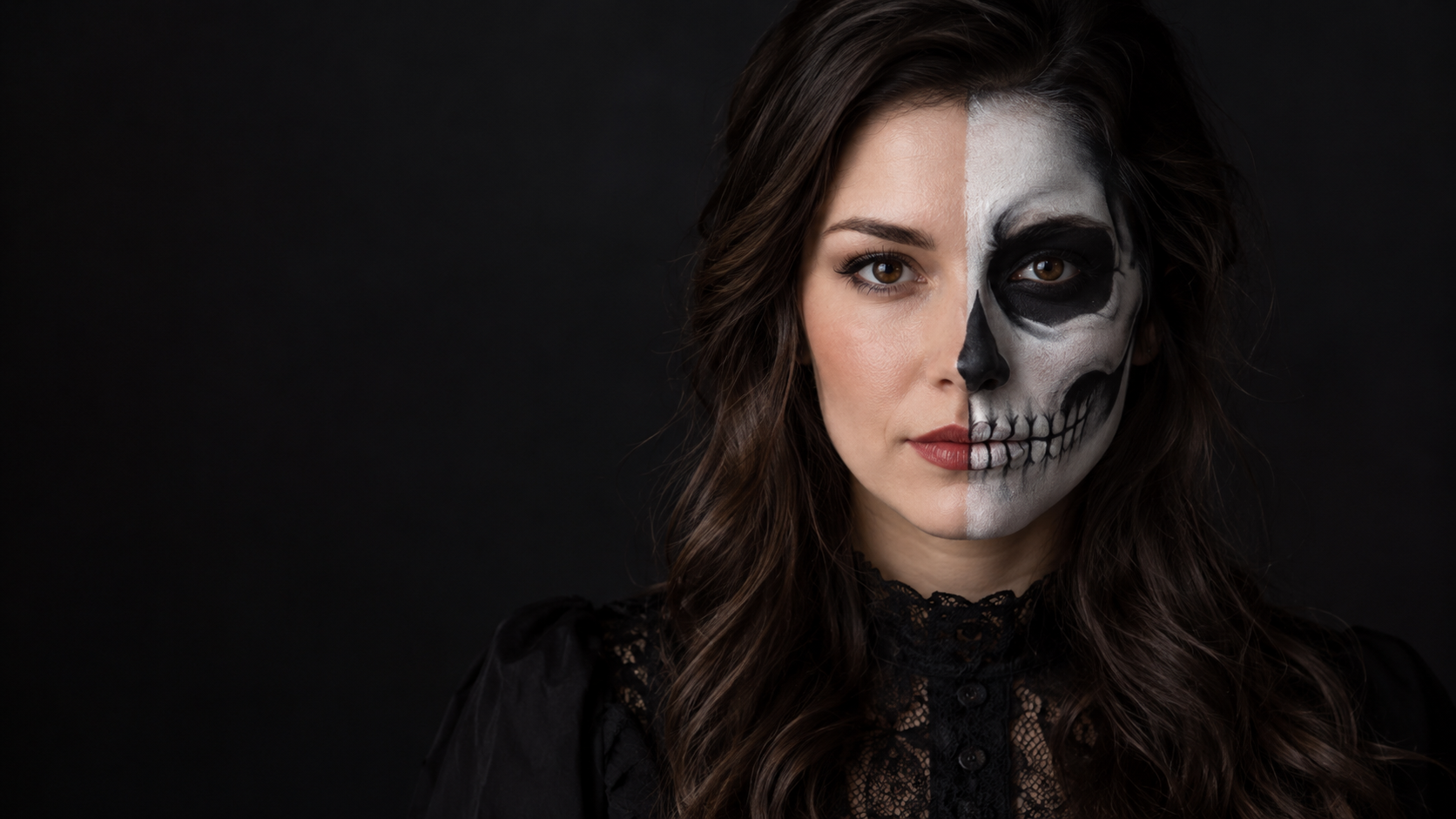 Half-Skull Close-Up: A fictional adult woman's face, one half natural and one half painted as a clearly anatomical white-and-charcoal skull, symmetrical studio portrait.