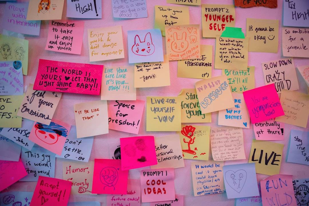 Colorful sticky notes on a wall, each with a short, handwritten positive word like 'love', 'joy', 'hope'.