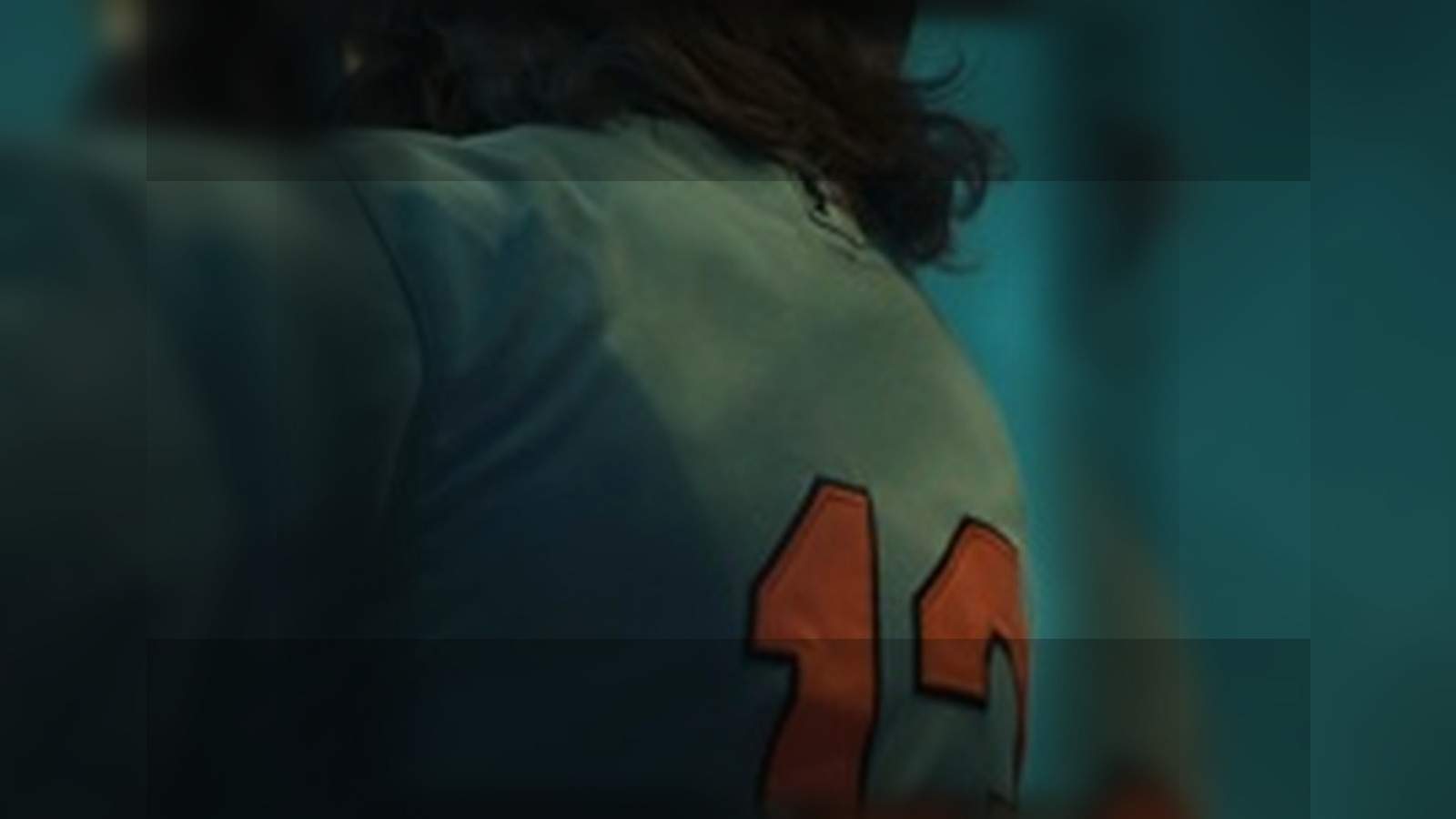 Back-view baseball player in a cinematic teal-lit portrait for styling exploration