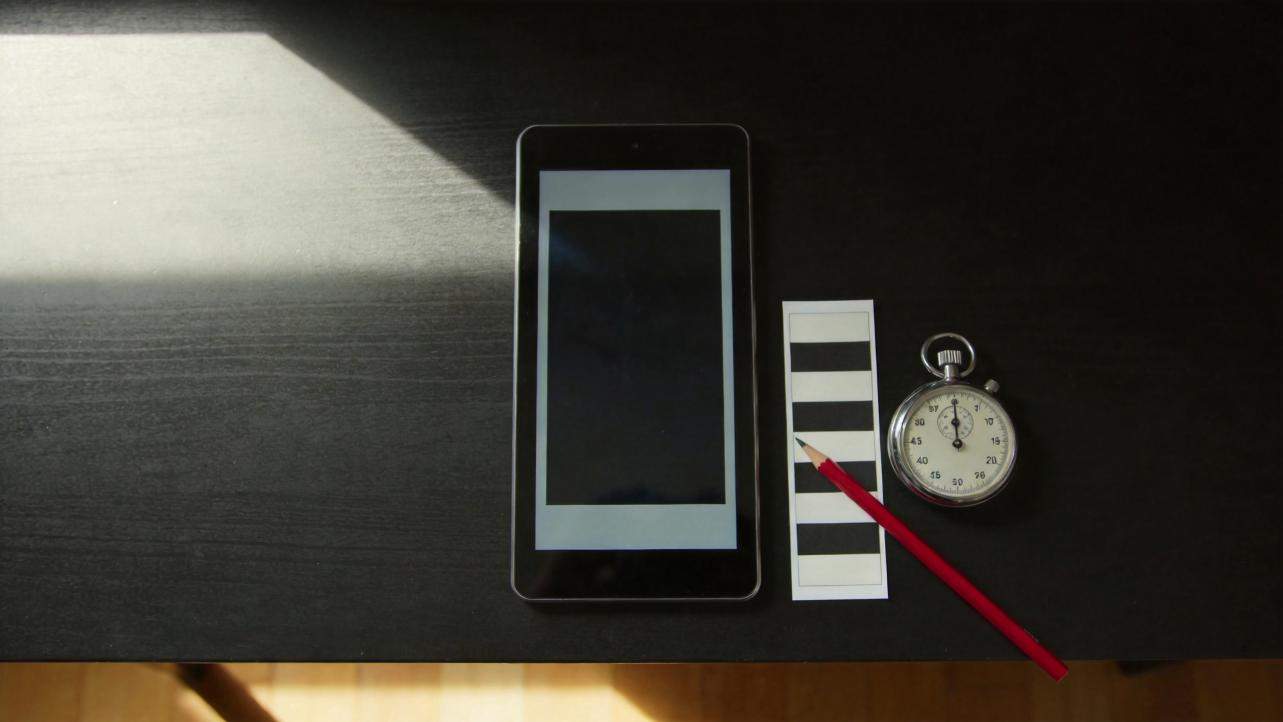 Smartphone mockup beside a subtitle text strip, pencil, and stopwatch on a dark desk