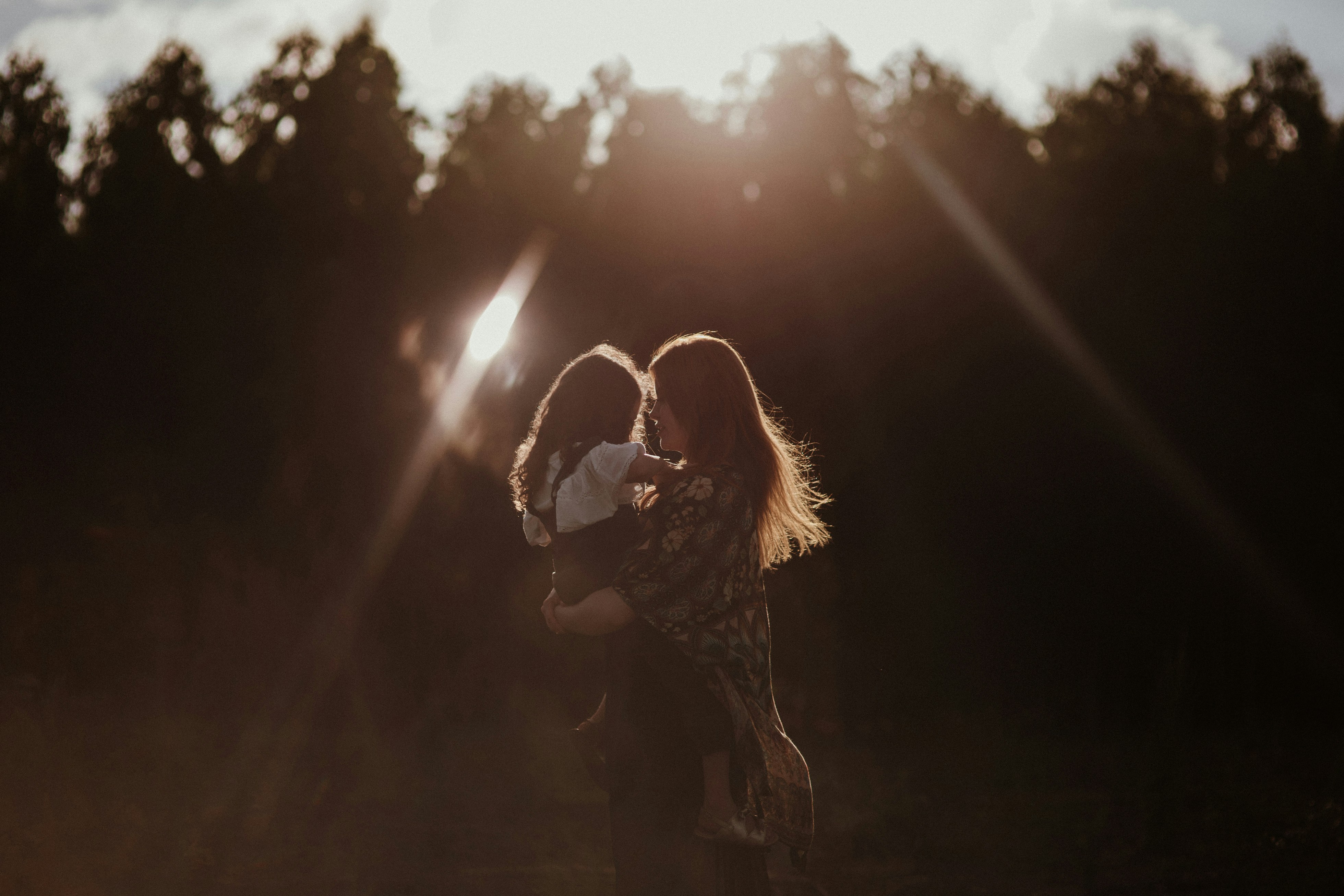 A heartwarming image of a mother and daughter embracing in a sunlit field, conveying love and warmth.