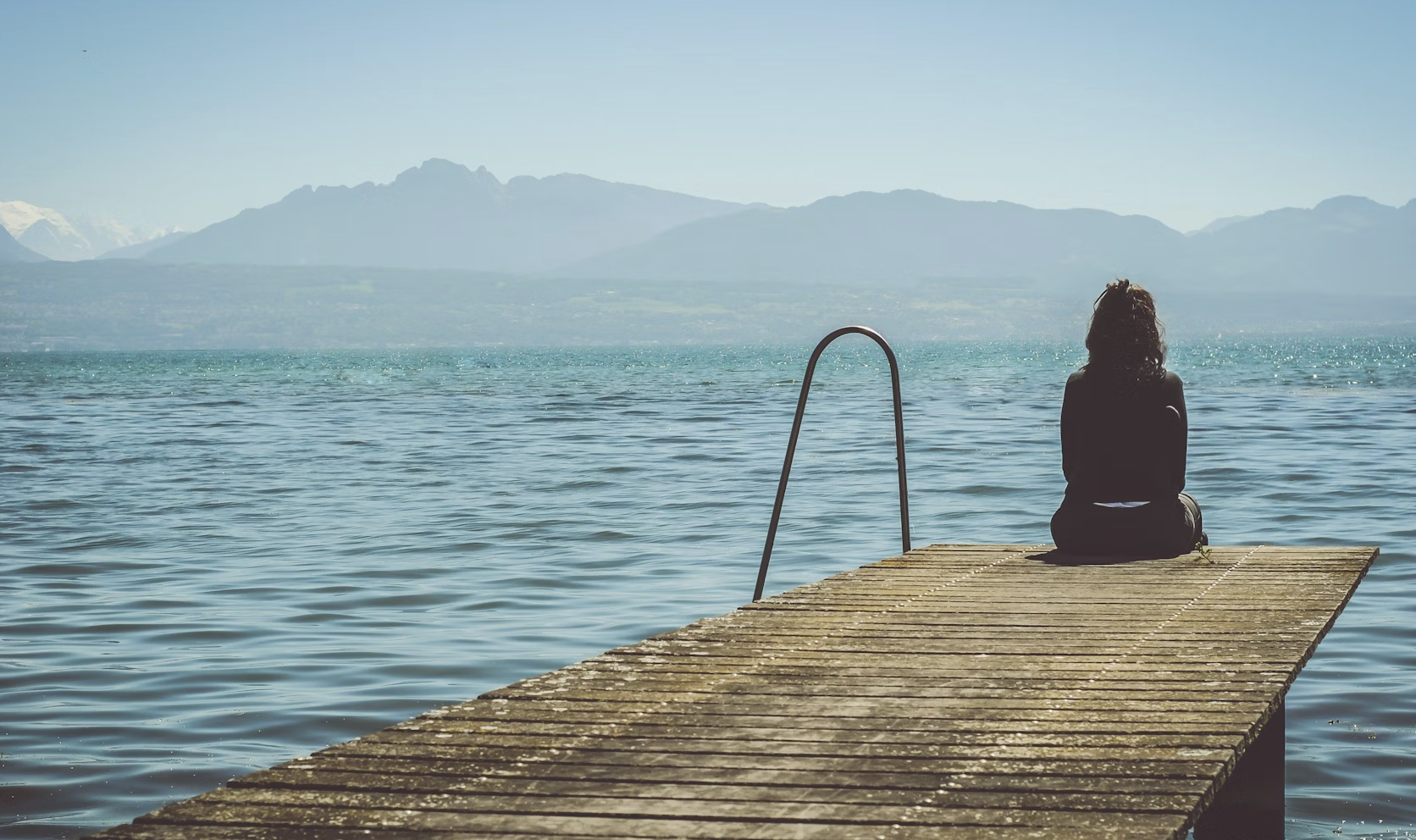 A person sitting alone in a dimly lit room, looking out a window at a rainy cityscape. The mood is melancholic and reflective, capturing the essence of sadness.