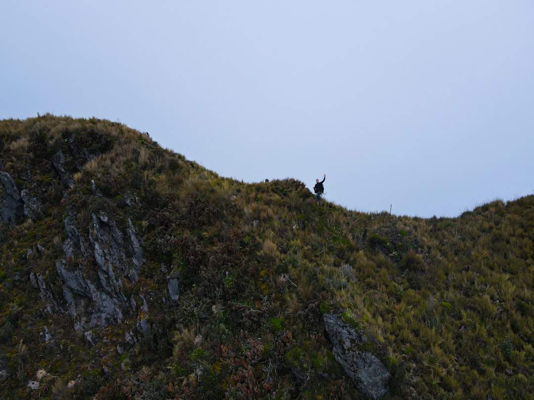 Una singola persona in piedi con sicurezza sulla cima di una montagna, guardando un vasto paesaggio.