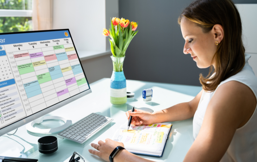Donna che organizza il proprio programma con un calendario e un pianificatore digitali, concentrandosi su strategie di presenza online.