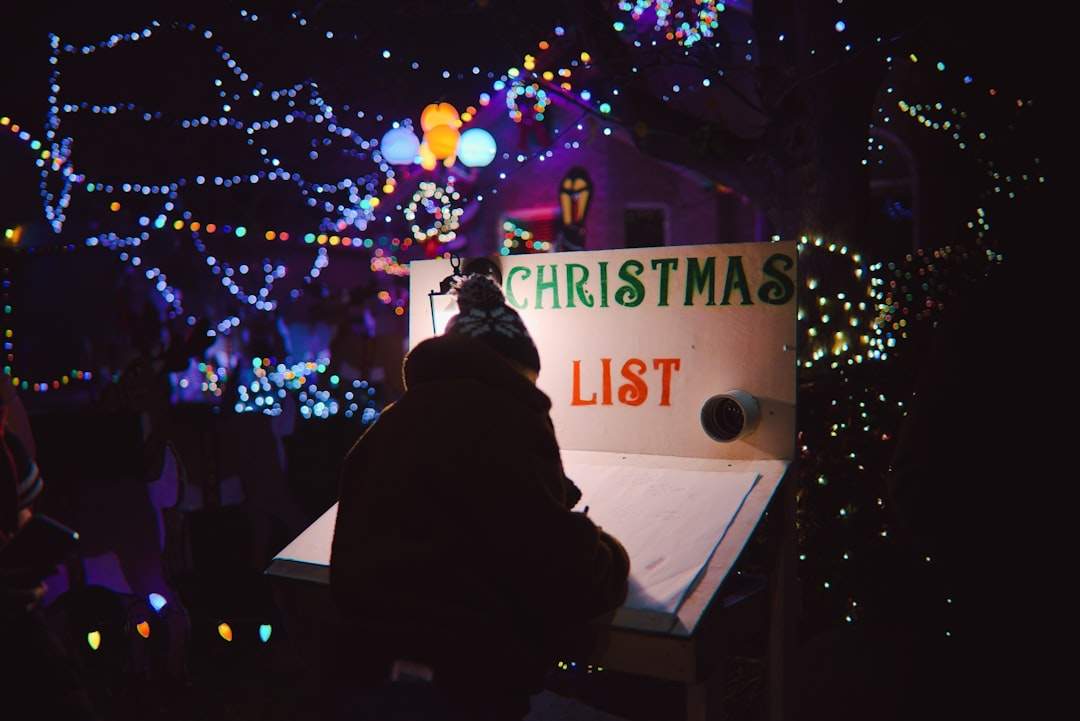A person writing on a Christmas list at a decorated desk