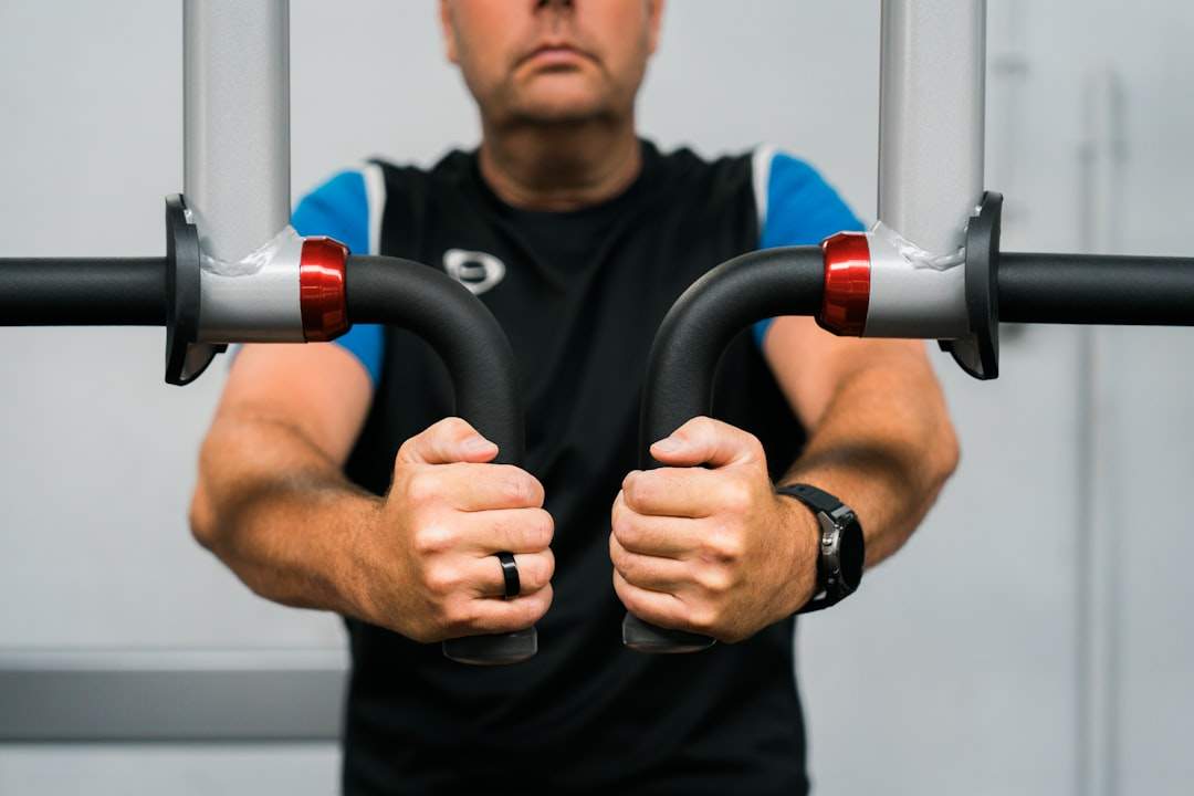 Человек, поднимающий тяжести в тренажерном зале с определенным выражением лица
