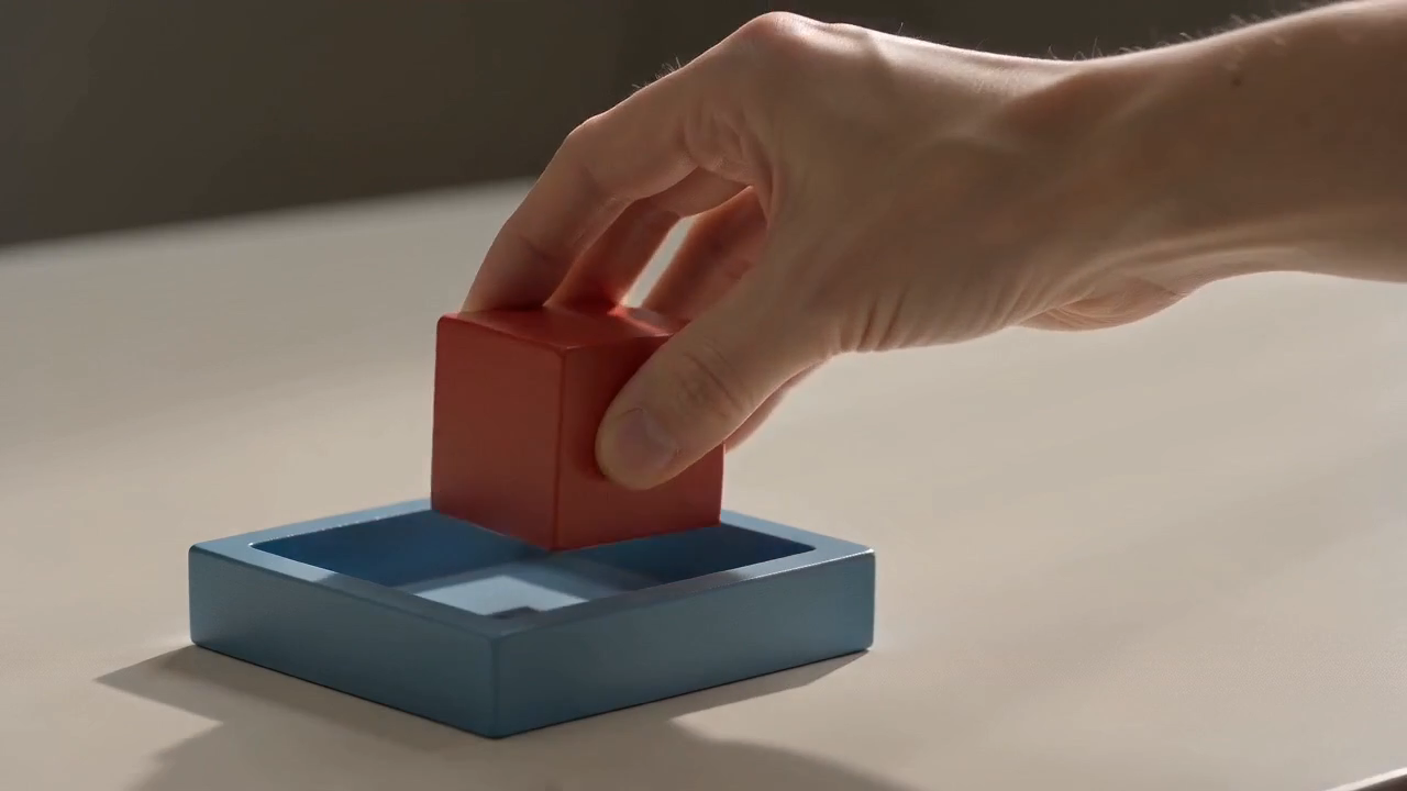Middle frame from the shorter CapCut export showing the hand moving the cube over the tray
