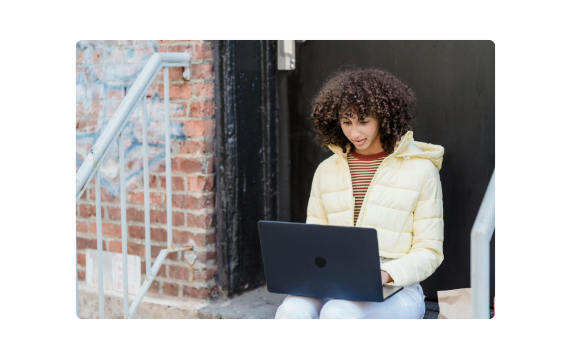 Giovane donna che usa un laptop all'aperto, rappresentando la creazione digitale di marchi e strategie per costruire una presenza online.