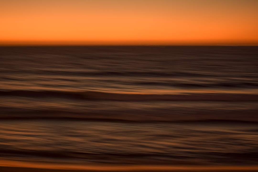 A wide-angle shot of a beautiful sunset over the ocean, with waves gently rolling in.