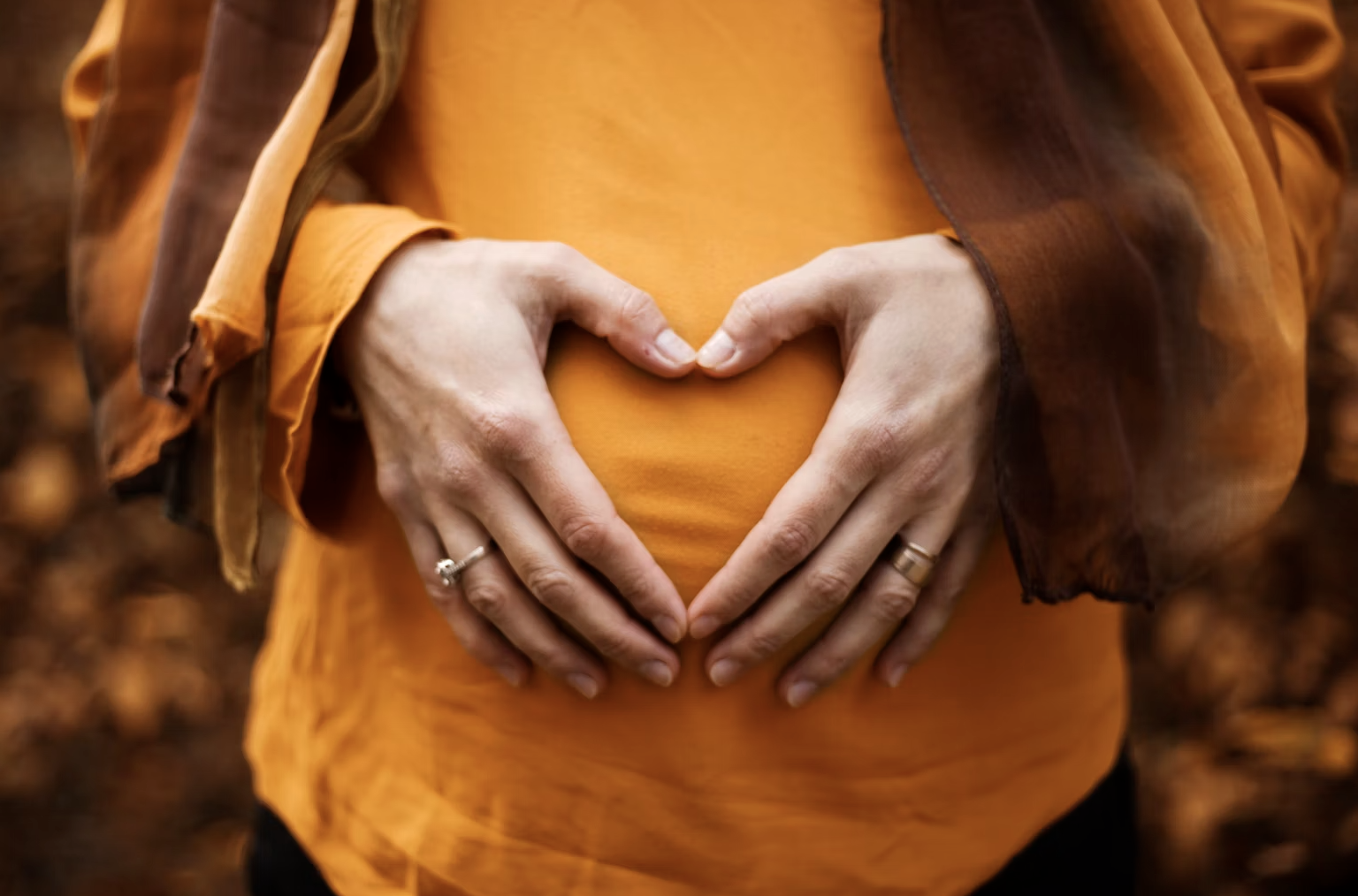 a pregnant woman smiling and holding her belly on mothers day