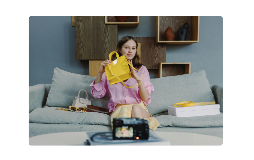 Ein Inhaltsersteller, der Amazon-Produktvideos filmt und eine gelbe Handtasche für KI-gestütztes eCommerce-Marketing präsentiert.