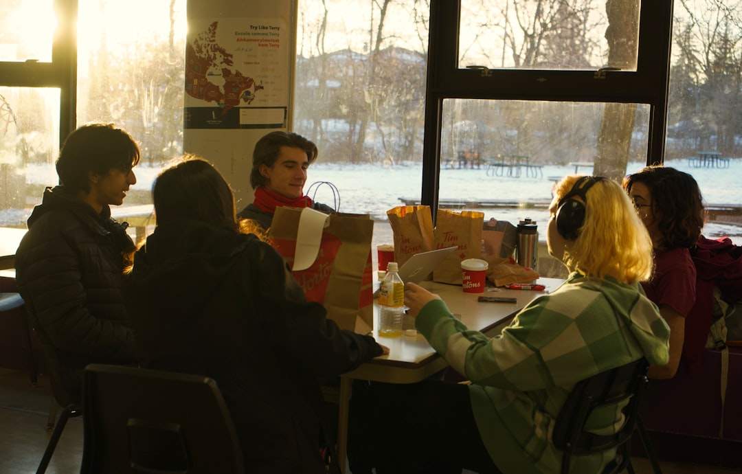 A group of diverse high school students brainstorming ideas in a classroom, with books and notepads scattered on the table.