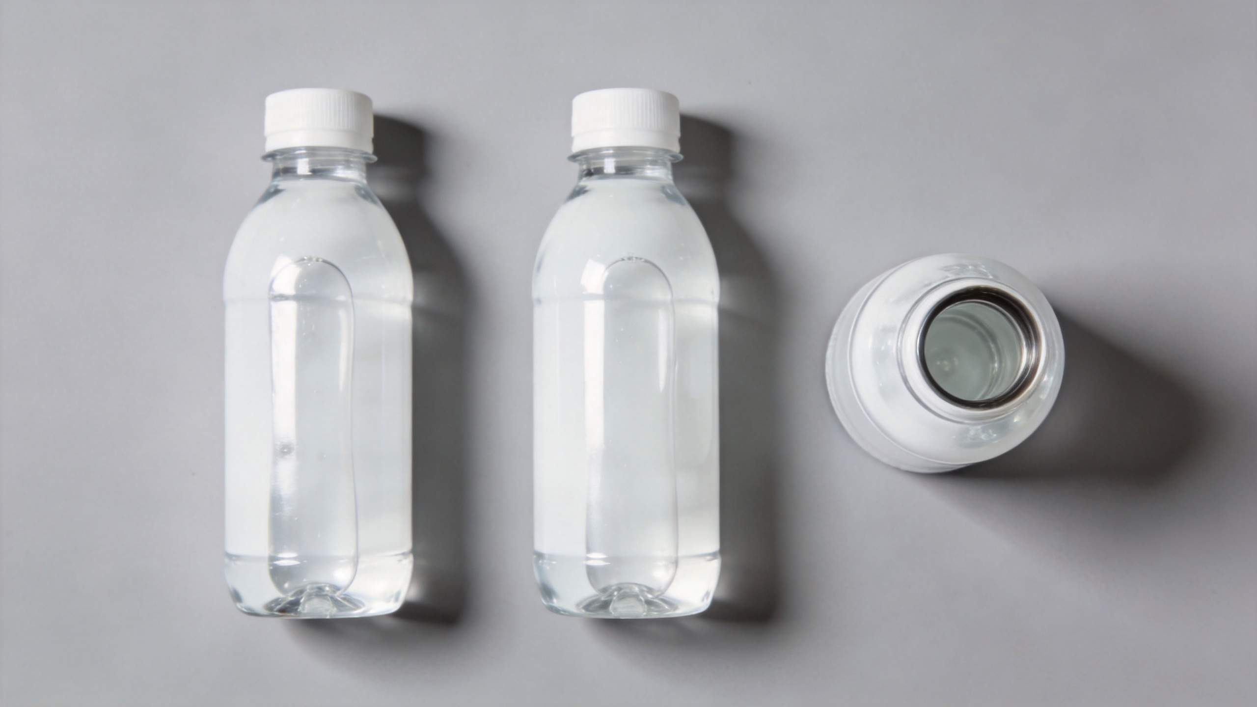 Two clear water bottles standing upright beside one lying on its side