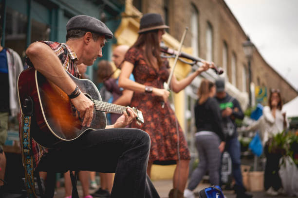 Street musician playing instrument with audience and street background