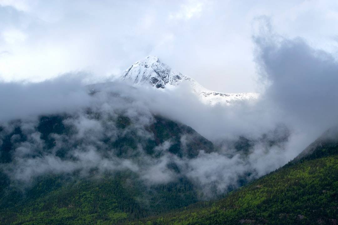 Una majestuosa cordillera con nubes arremolinándose alrededor de los picos, inspirando asombro y maravilla.