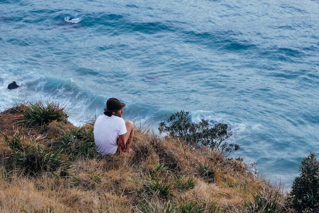 A person sitting on a cliff overlooking a stormy sea, looking contemplative.
