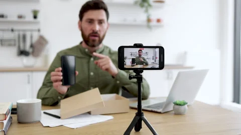 Vlogueiro de tecnologia fazendo unboxing de um novo dispositivo em frente à câmera.