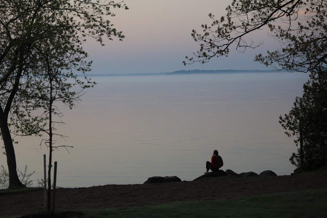 Een persoon die mediteert bij zonsopgang, met uitzicht op een kalm meer.
