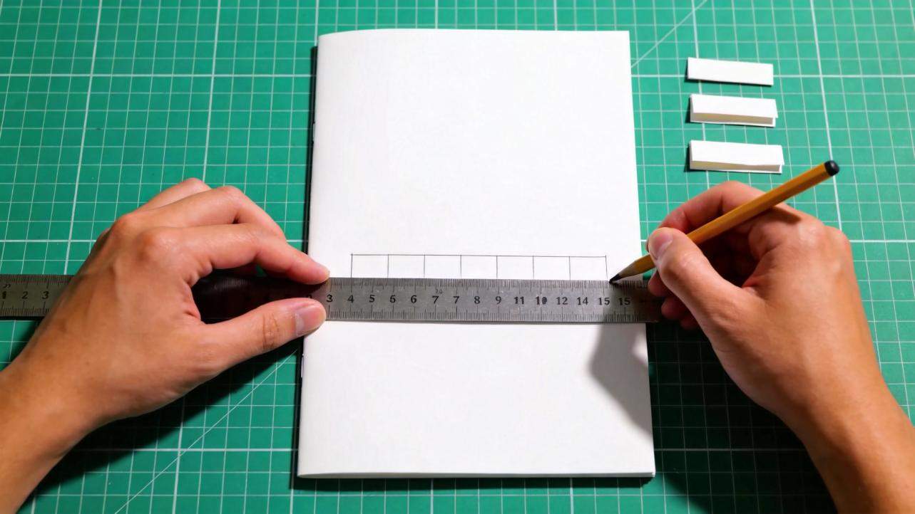 Hands use a ruler and pencil to mark tear-off tab sections on a blank flyer