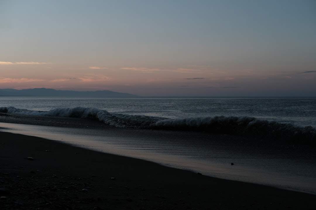 A serene, empty beach at sunrise with gentle waves lapping at the shore.