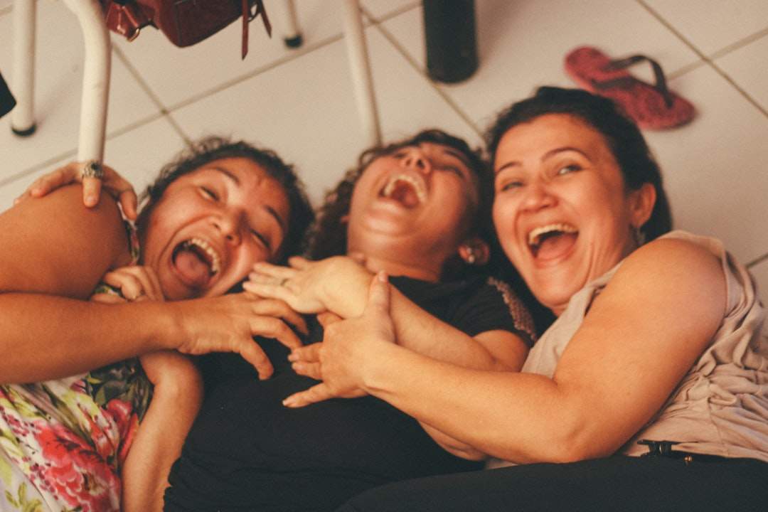 Una persona che ride di cuore, con uno sfondo sfocato di una festa vivace o di un incontro sociale.