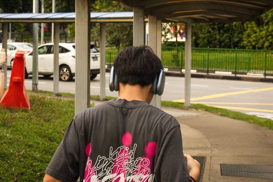 A person wearing headphones and listening to audio on their smartphone while walking.