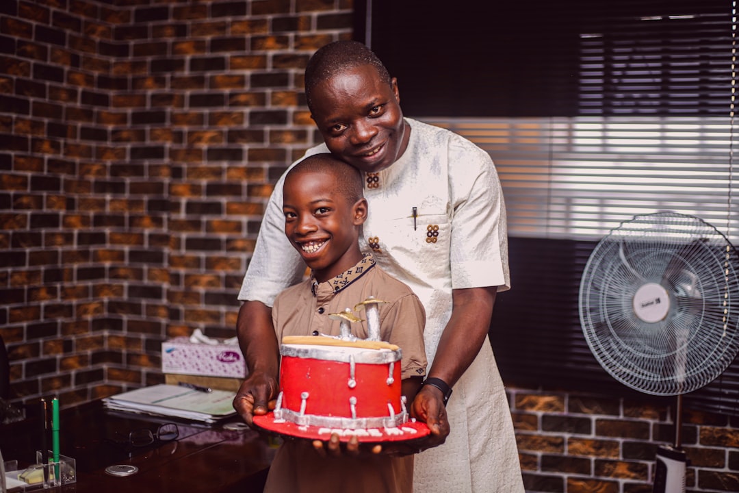 A father and his child smiling and celebrating a birthday with a cake